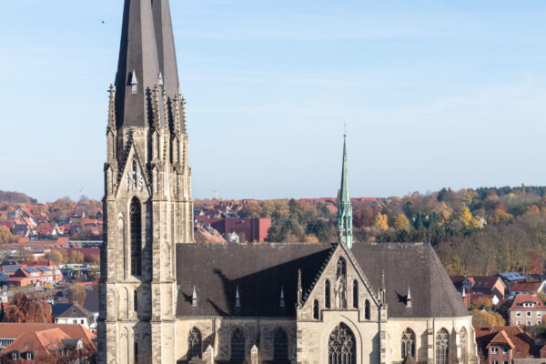 Große Kirche mit sehr hohem Turm und einer Stadt drumherum wobei die Kirche als Mittelpunkt des Bildes dient