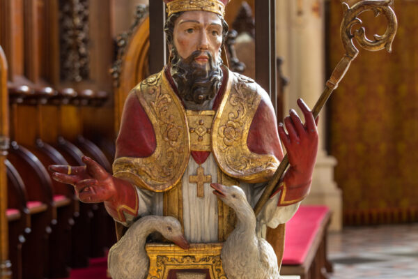 Figur eines Heiligen mit zwei Gänsen an seiner Seite und rot goldener Kleidung