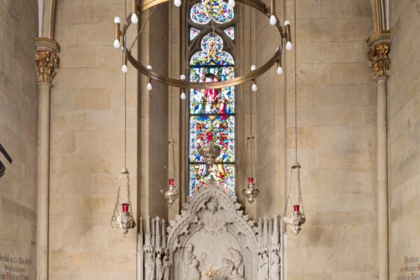 Innenansicht einer Kirche mit verzierten Fenstern, hoher Decke und einem Schrein in der Mitte