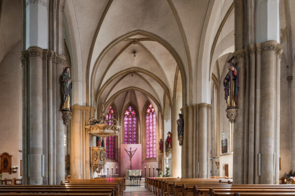 Innenansicht einer Kirche mit vielen Bänken und vorne einem Altar sowie einem Kreuz