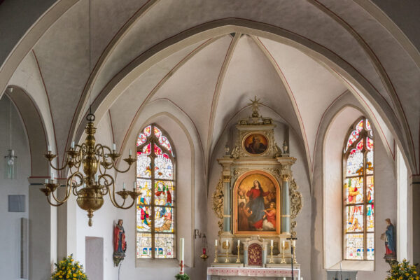 Altar mit Heiligtum mit einer Darstellung der heiligen Maria und mehreh Bänken sowie kunstvolle Fenster