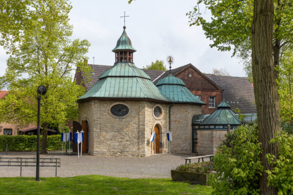 Kleine Kapelle mit annähernd runden Dach mit Kreuz auf der Spitze und einigen runden Fenstern zwei Anbauten mit ähnlichen Stil aber kleiner werdend