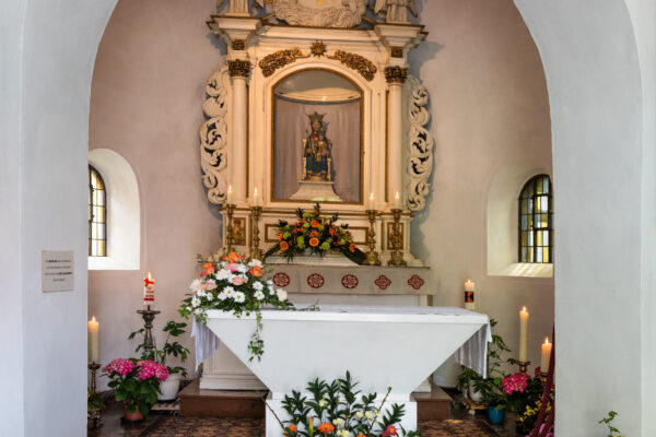Heiligtum Marienbild mit kleinem Tisch und vielen Blumen sowie Kerzen