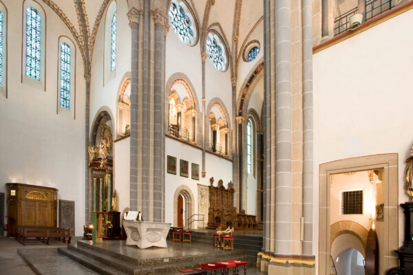 Altar einer Kirche mit zwei großen Säulen sher hoher Decke und Verzierungen an den Wänden