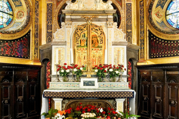 Schrein einer Kapelle mit Blumen davor und einer Wand und Decke mit gold verzierten Bilder
