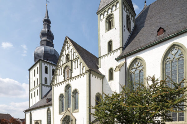 Kirche von Aussen im Vordergrund zwei Türme und der Eingang mit verzierter Aussenwand