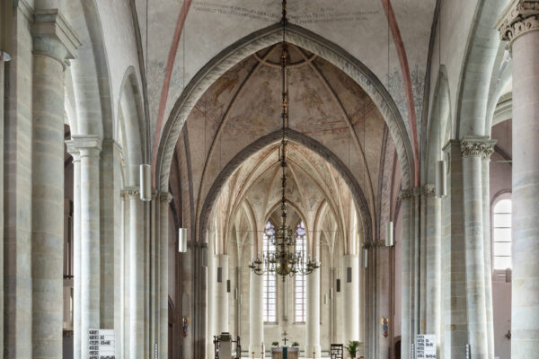 Ansicht vom hintersten Ende der Kirche nach vorne zum Altar mit vielen Bänken und einer hohen Decke