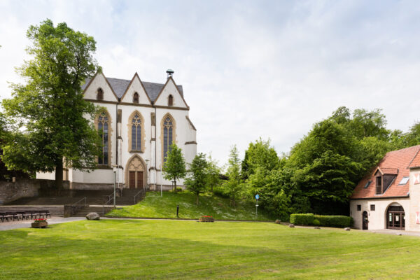 Quadratische Kirche mit großen Fenstern und Wiese davor